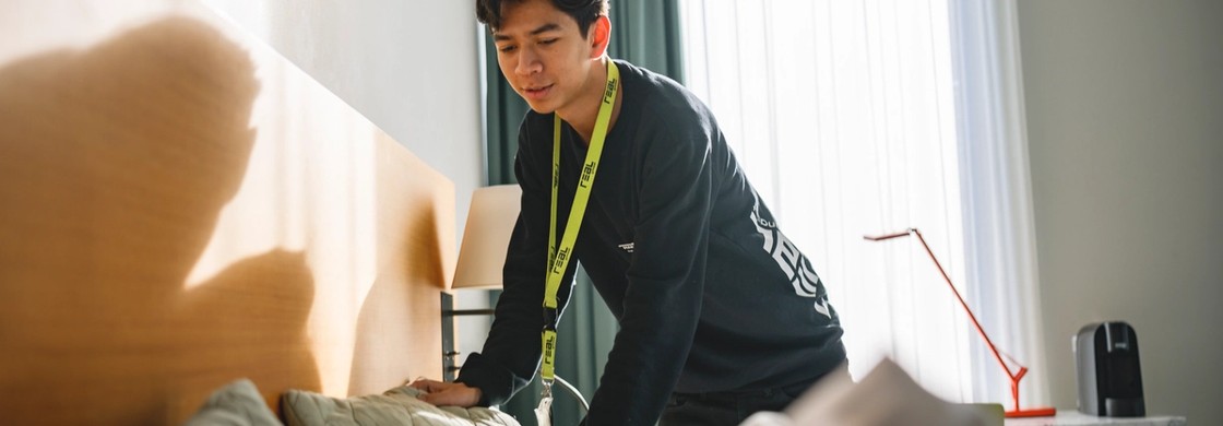 Leende gymnasieelev städar i ett hotellrum