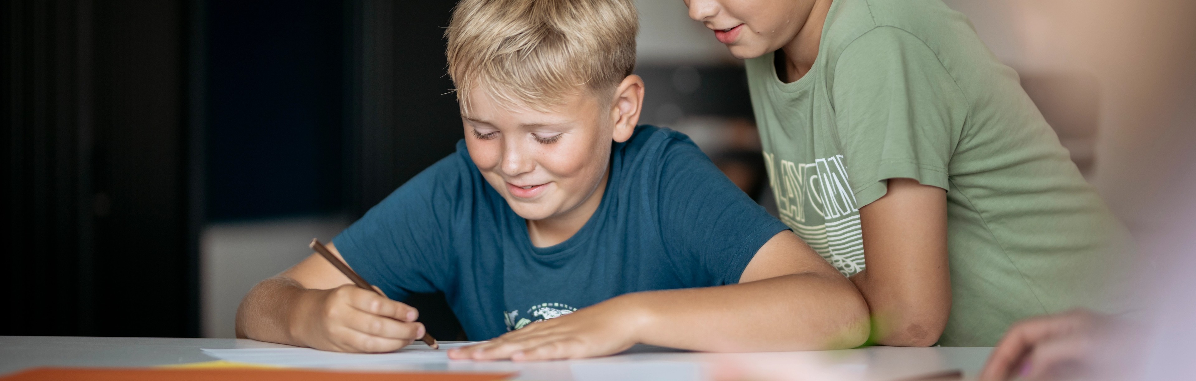 Elev skriver och en annan elev tittar över axeln