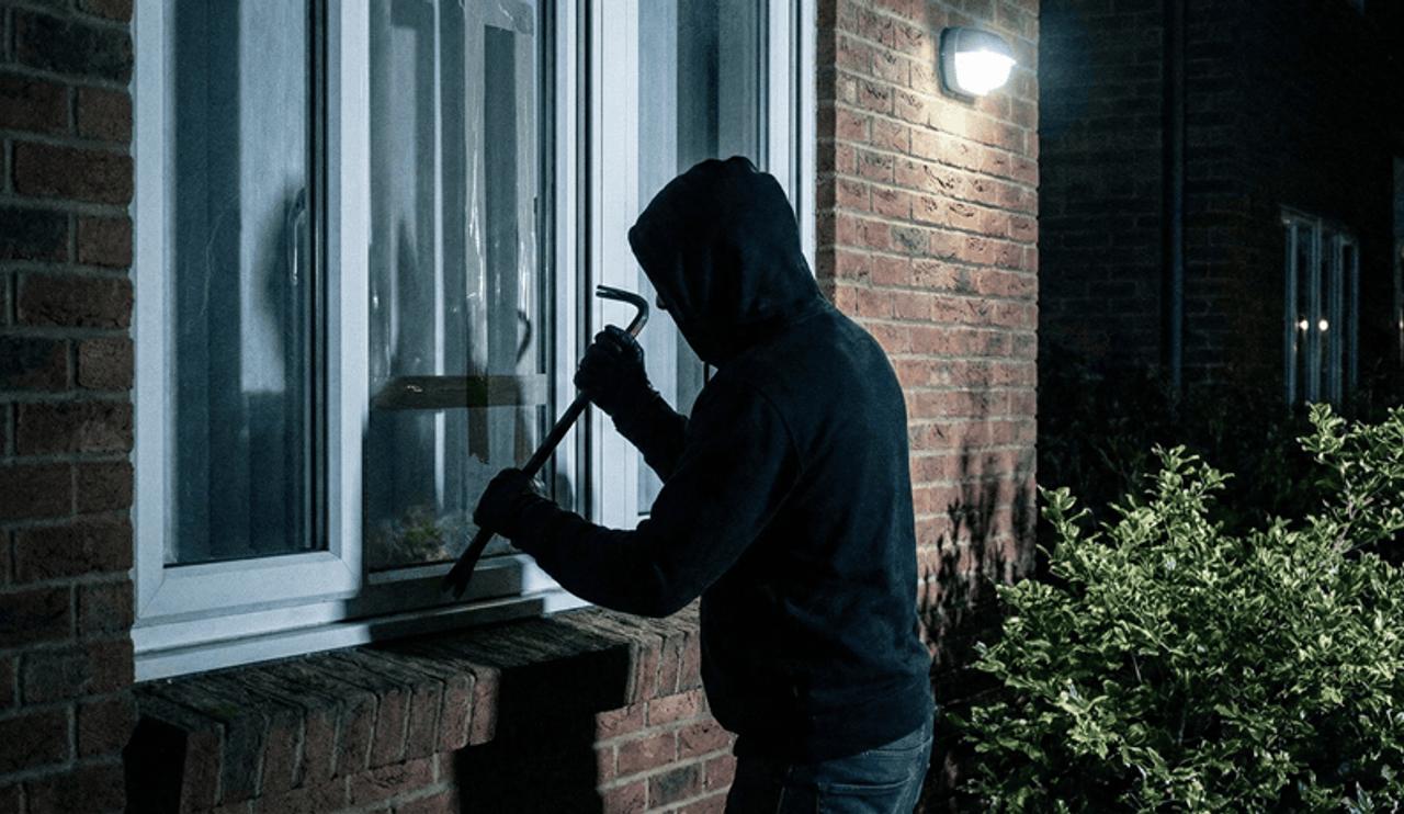 home intruder attempting to gain access to a home with a crowbar at a window