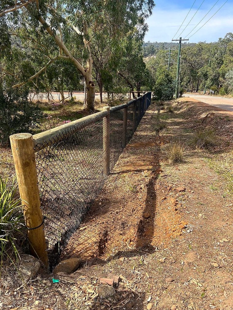 Rural chain-mesh fencing with a timber strainer post on a sloping Perth Hills block