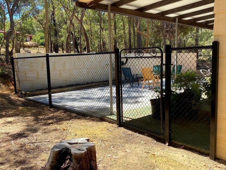 Black chain-mesh enclosure and gate around a paved outdoor area on a Perth Hills property