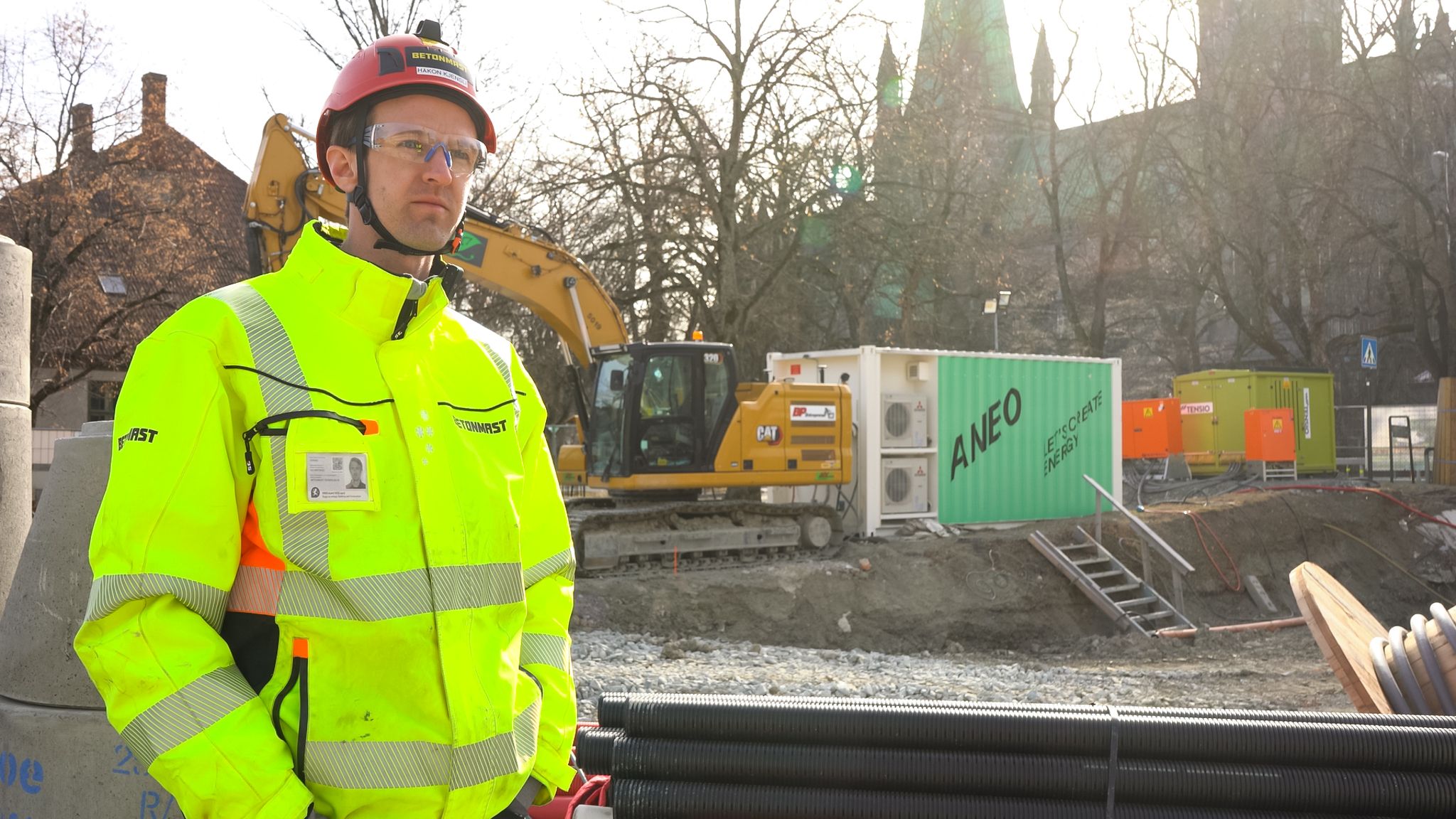 Elektrisk gravmaskin på byggeplass med ladecontainer fra Aneo