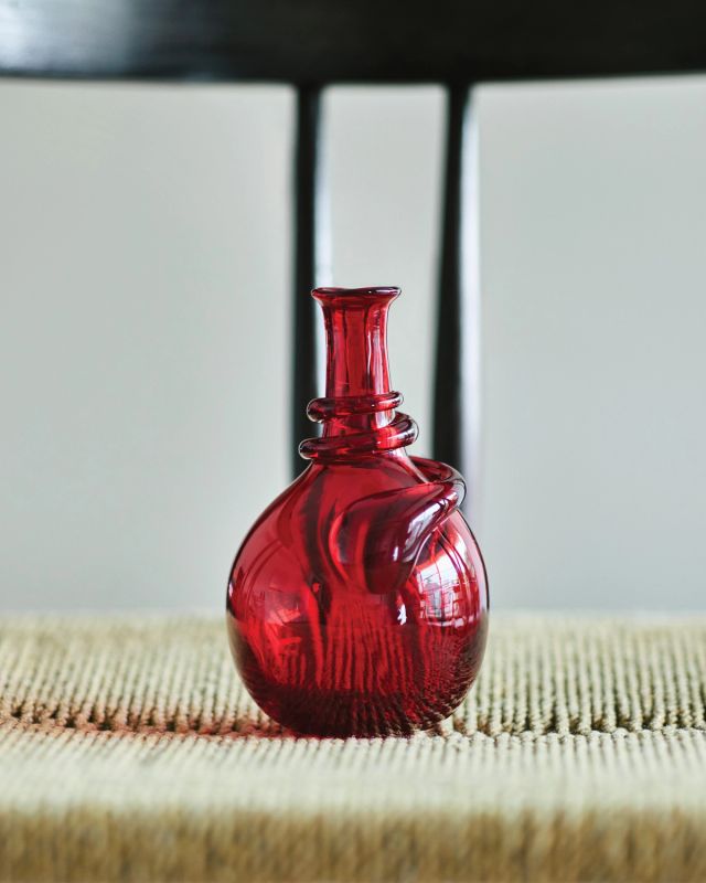 Hand-blown red glass vase featuring a rounded silhouette and sculptural detail near the neck.