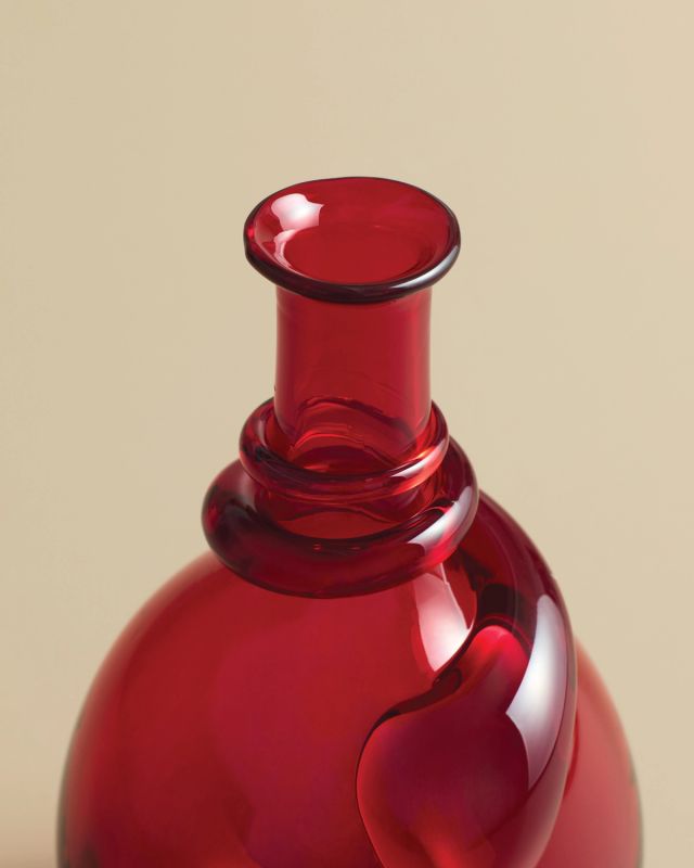 Hand-blown red glass vase featuring a rounded silhouette and sculptural detail near the neck.