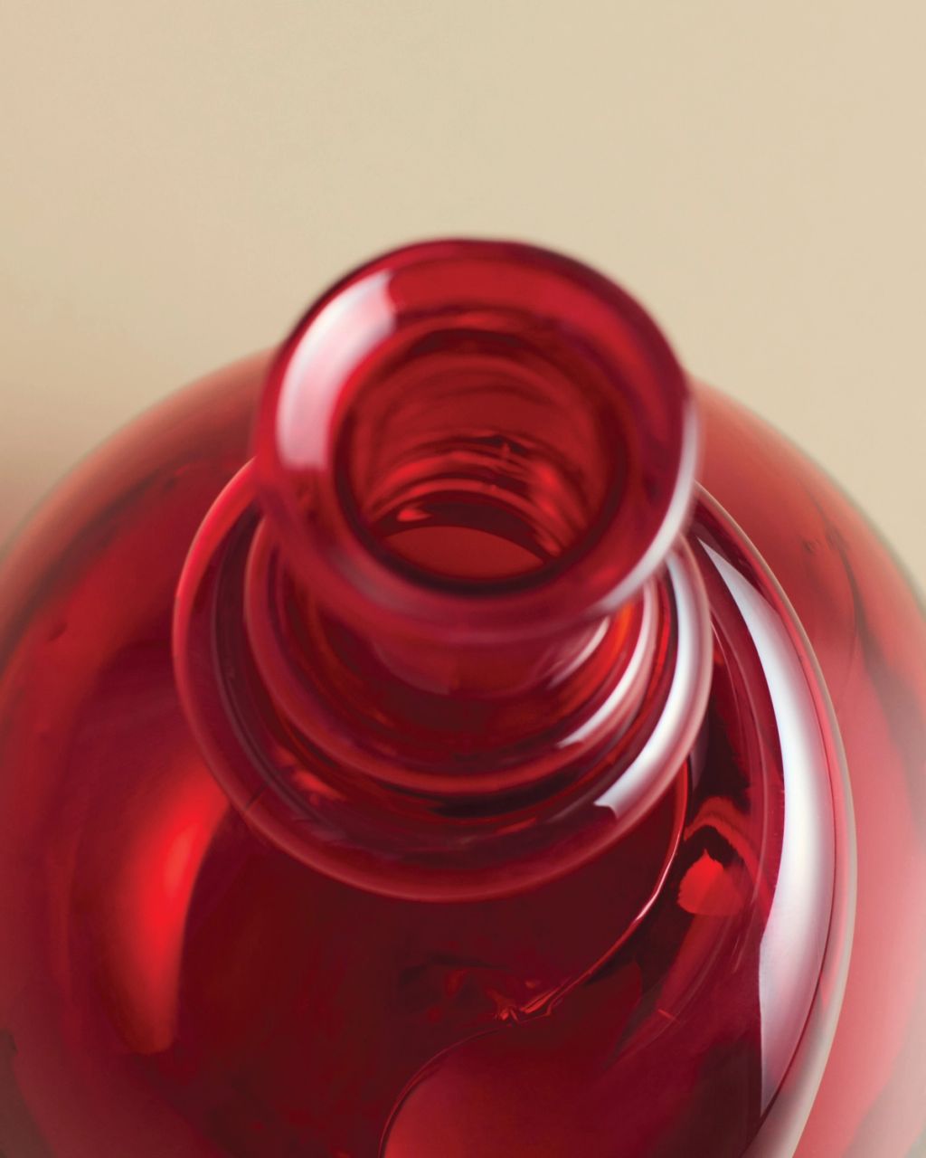 Hand-blown red glass vase featuring a rounded silhouette and sculptural detail near the neck.