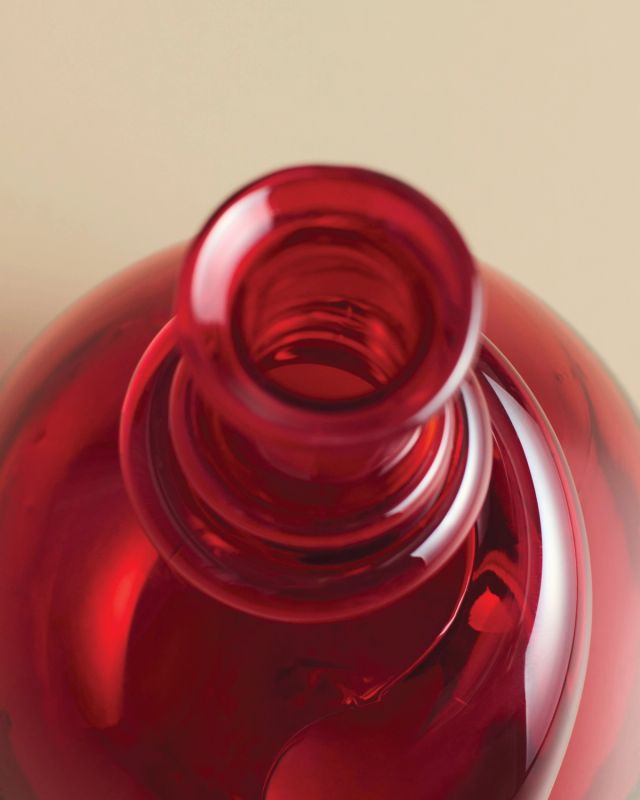 Hand-blown red glass vase featuring a rounded silhouette and sculptural detail near the neck.