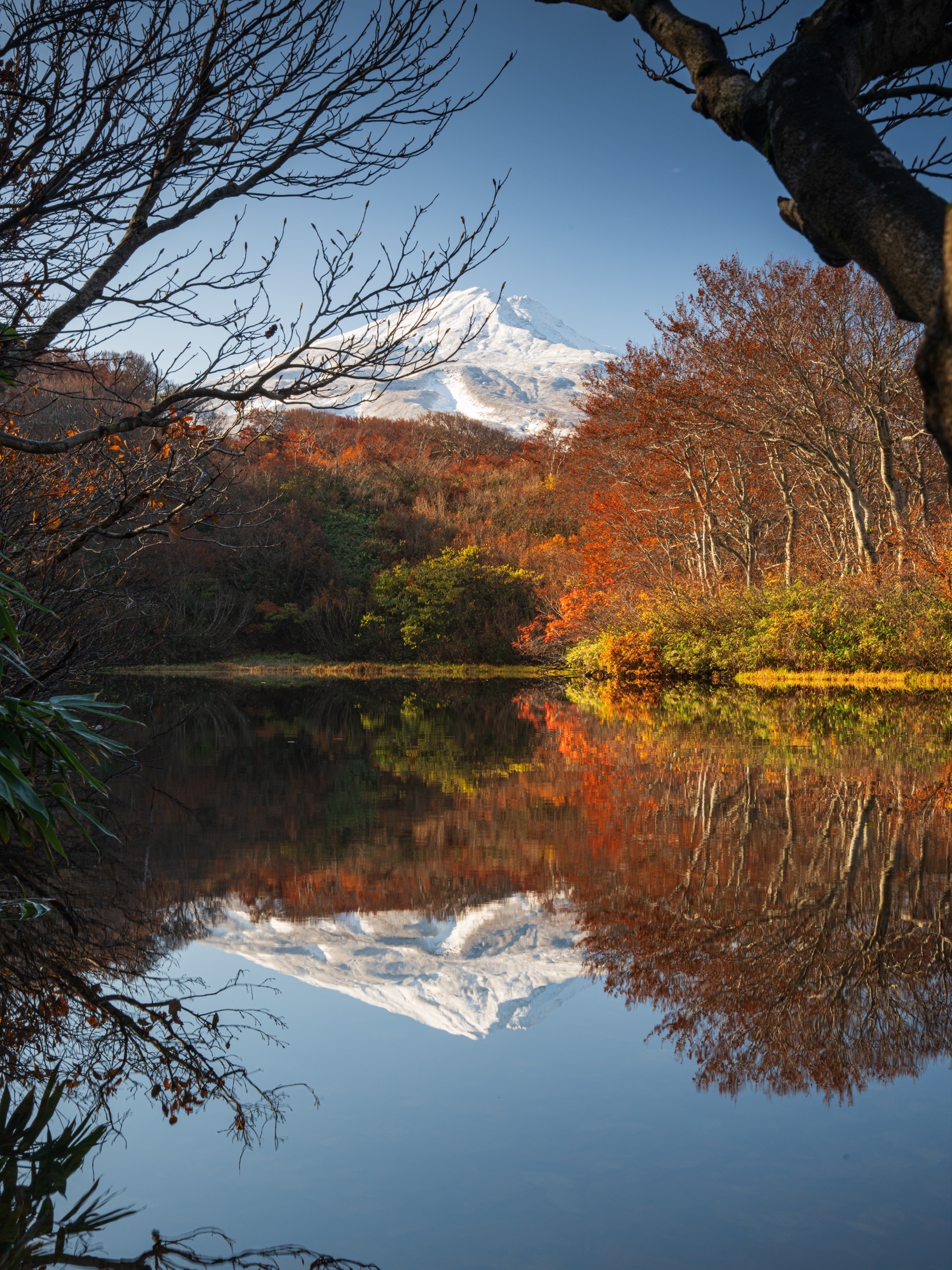 Le mont Chōkai enneigé et les couleurs d’automne se reflètent dans un étang calme.