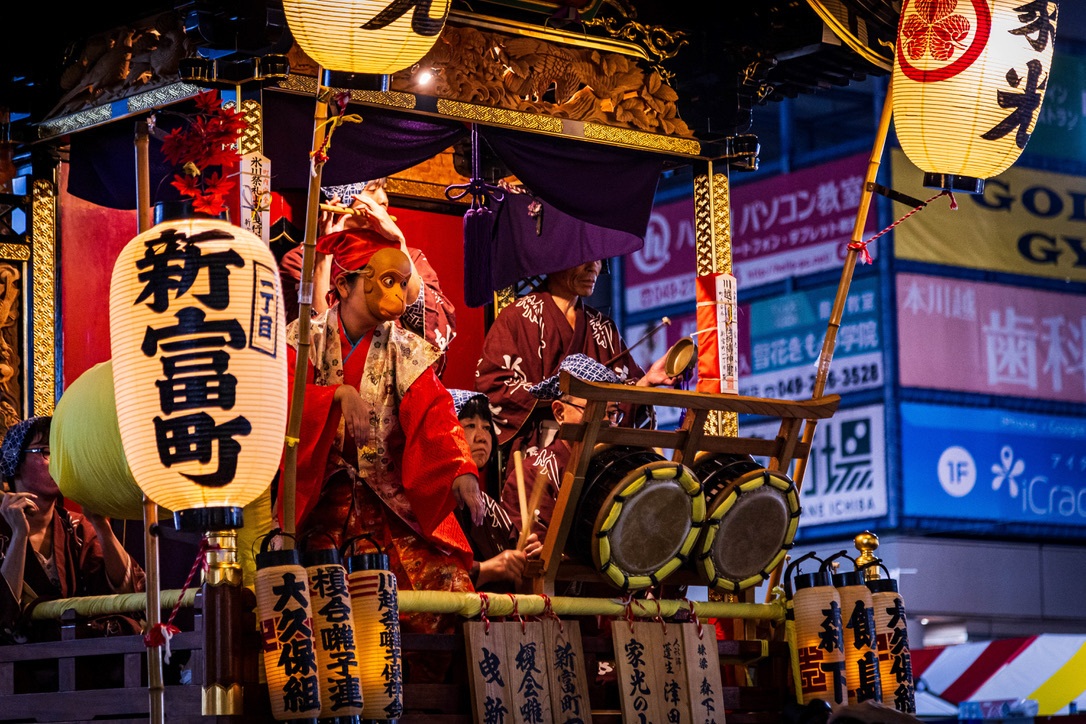 Musiciens et danseurs animent un char traditionnel lors d’un matsuri nocturne.