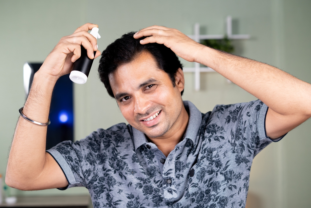 man spraying product on hair