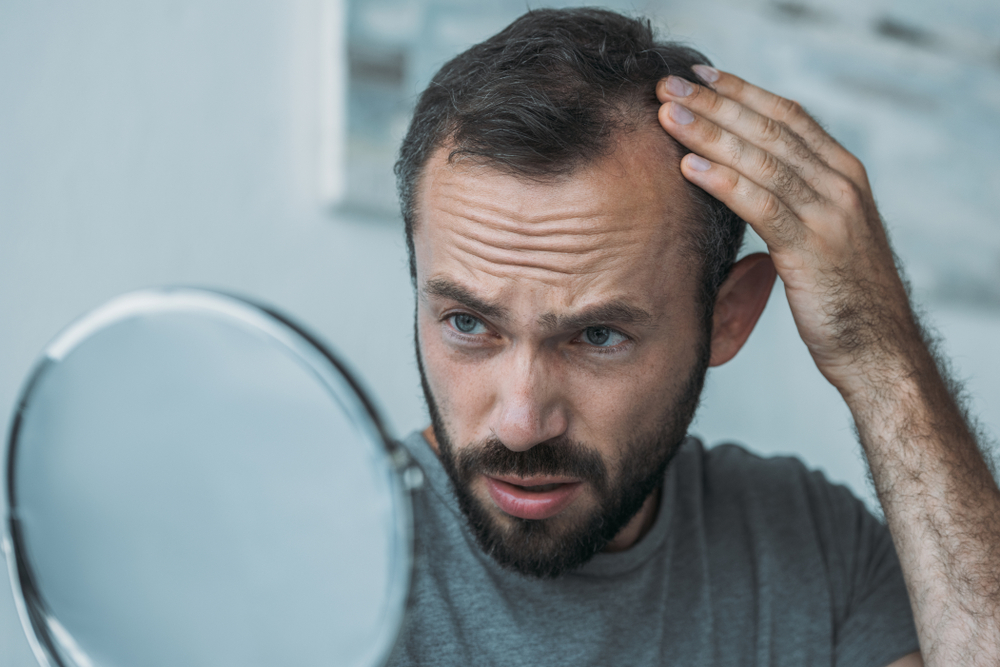 man checking hair in the mirror