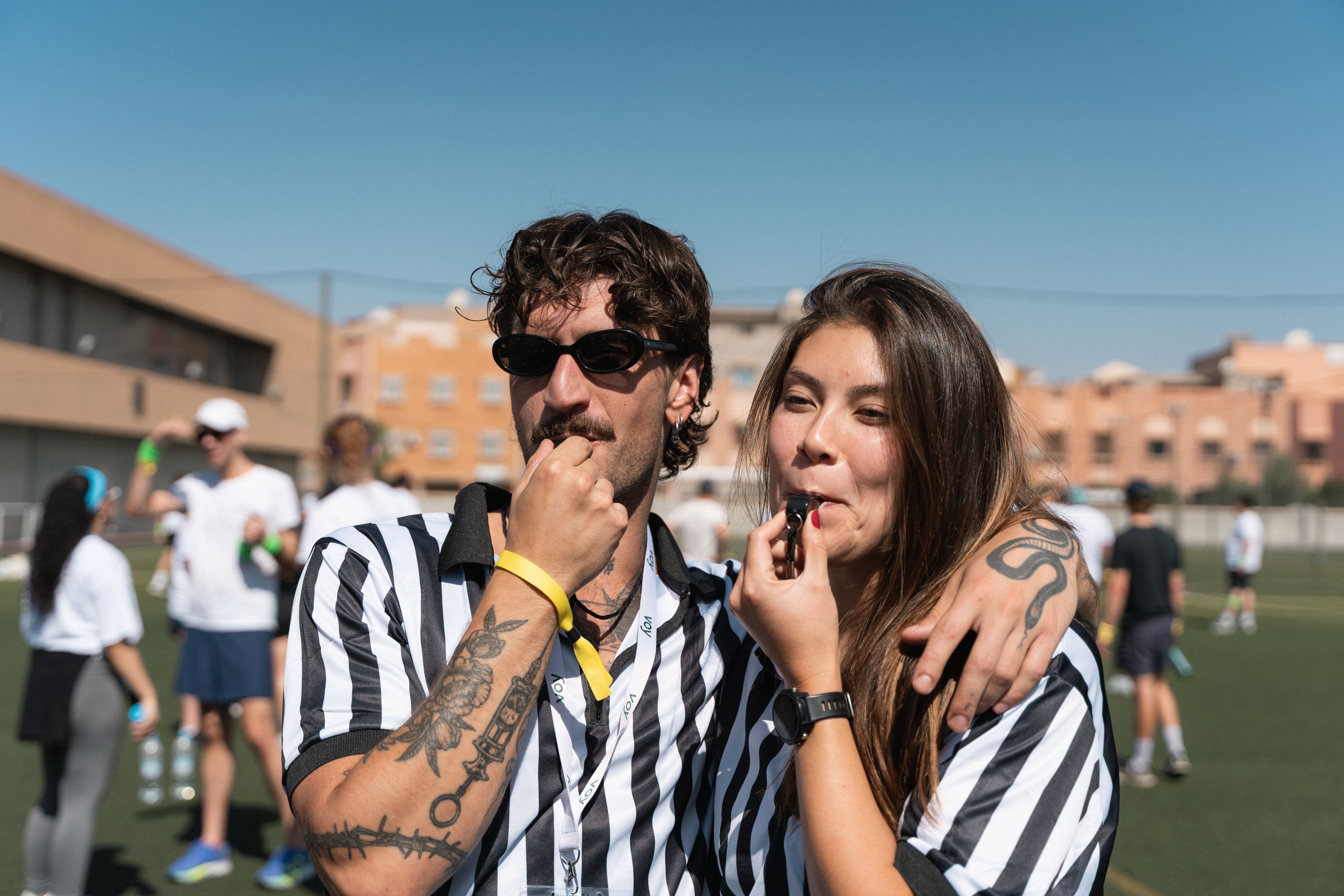 Two Voy employees dressed as referees blowing whistles