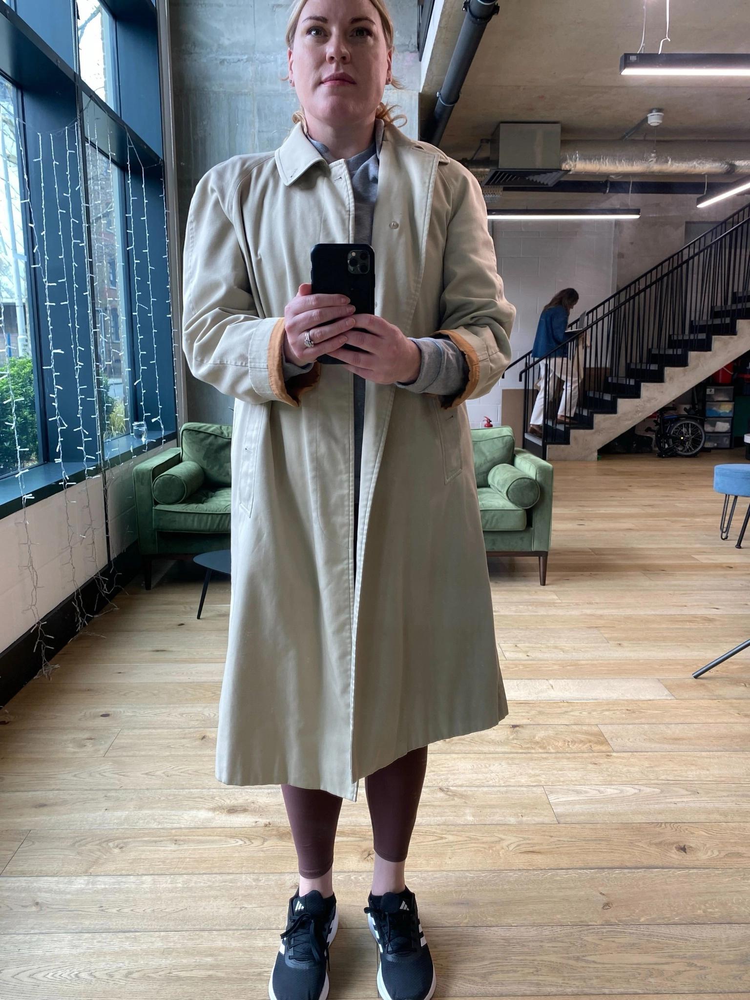 Full-body photo of a person wearing a long, loose, oversized coat over other clothing, making body shape not clearly visible.
