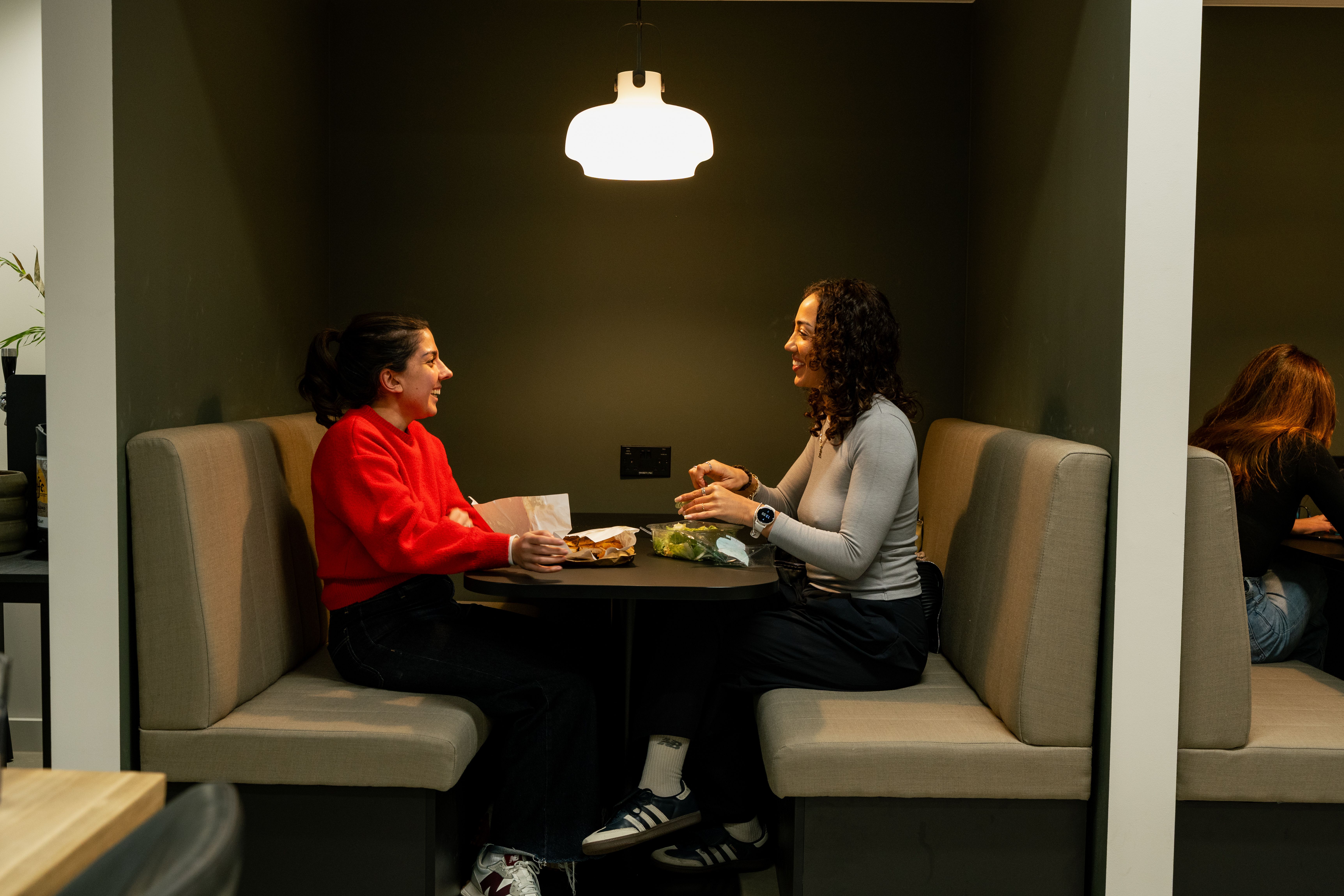 Two Voy employees sit in a booth eating lunch together