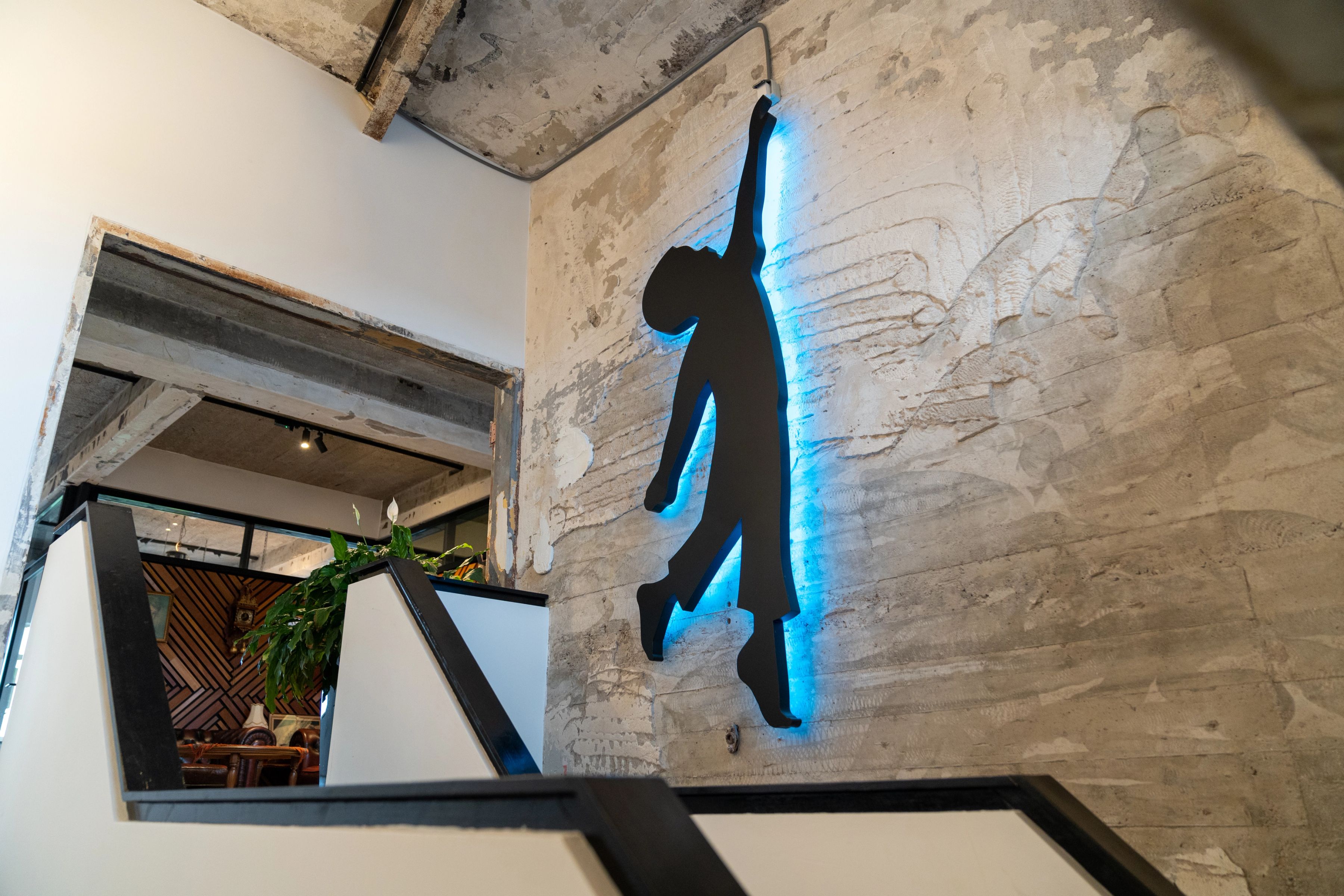 Lichtgevend logo van Tommy boven een trap
