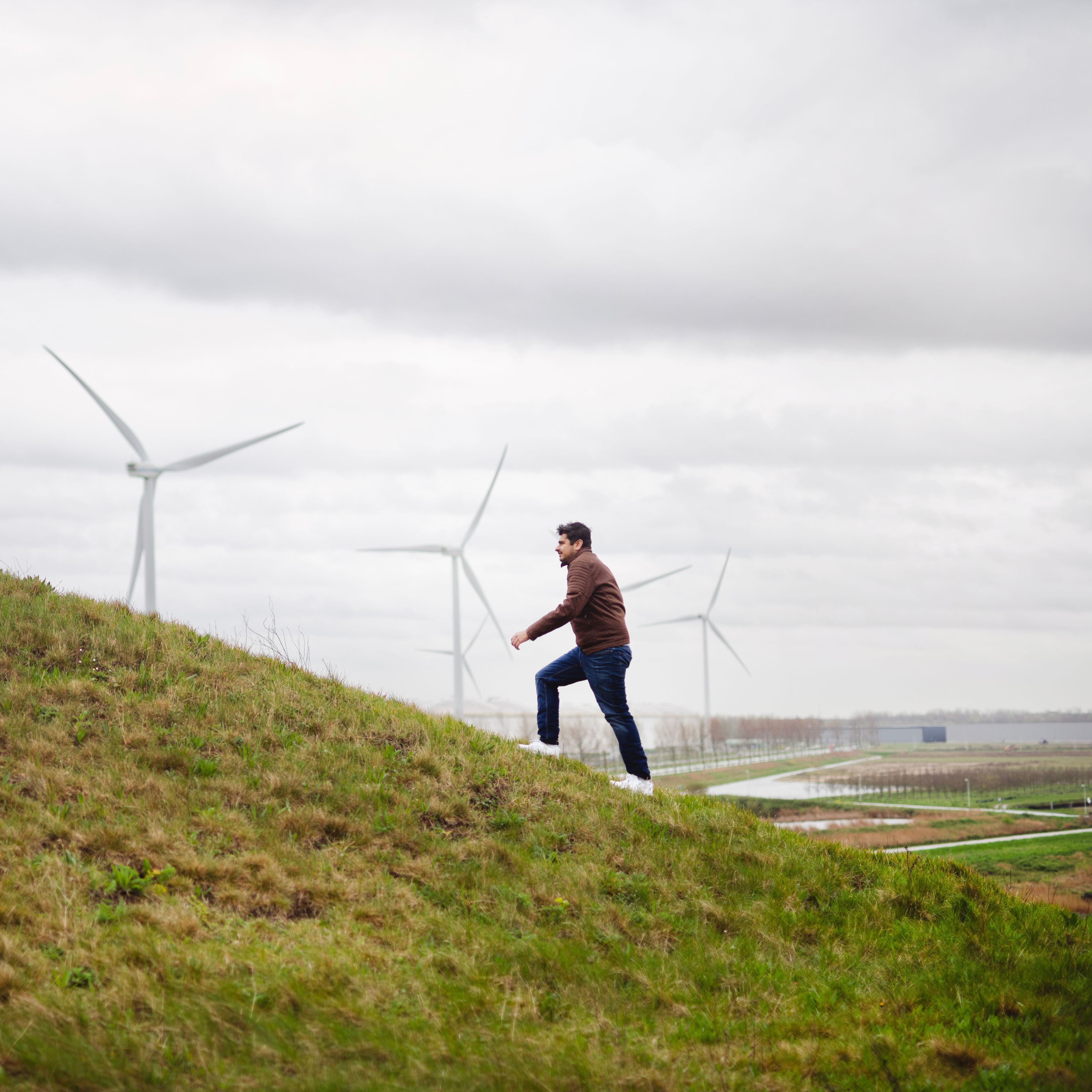 Man loopt heuvel op bij windmolen