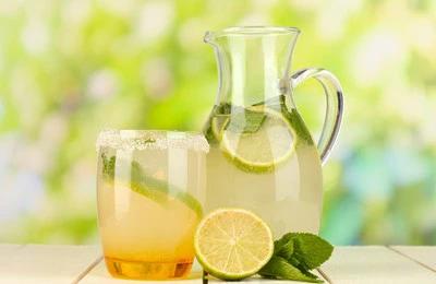 Pitcher and glass of iced lemonade with lime slices
