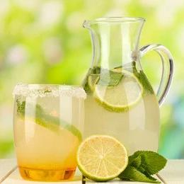 Pitcher and glass of iced lemonade with lime slices