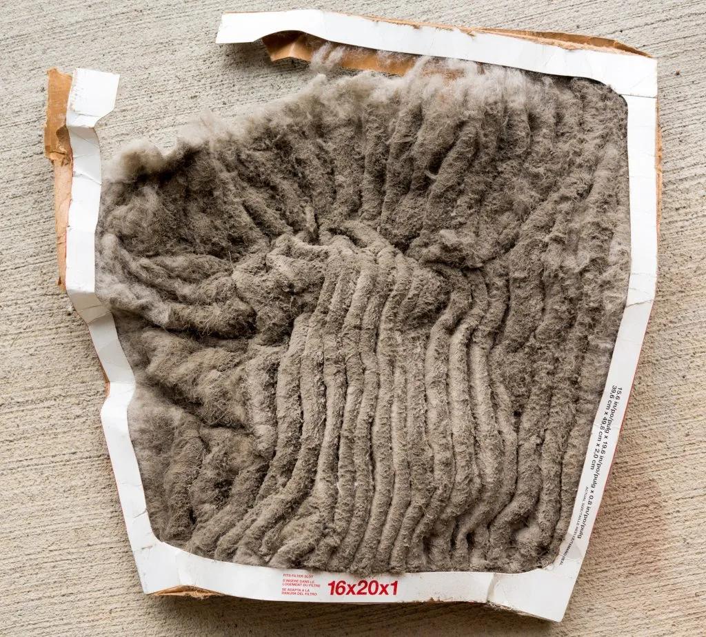 Used 16x20x1 air filter completely covered in gray dust