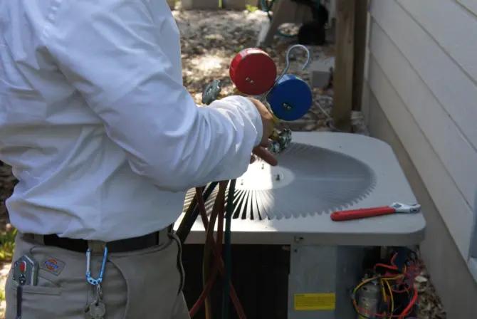 Technician checking an outdoor HVAC unit with refrigerant gauges