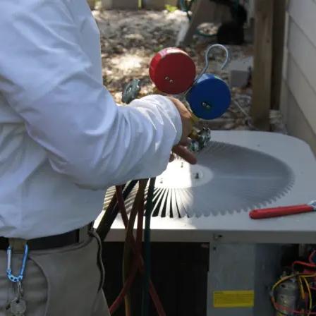 Technician checking an outdoor HVAC unit with refrigerant gauges