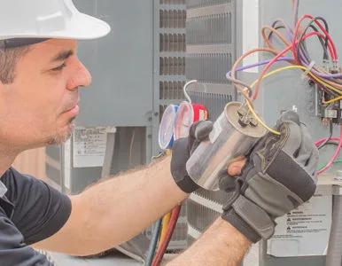 Technician in a hard hat wiring a furnace control board