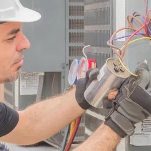 Technician in a hard hat wiring a furnace control board