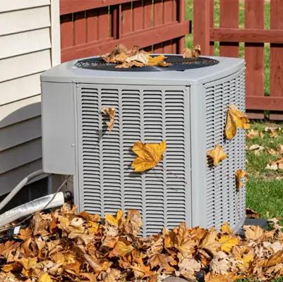 Outdoor air conditioning unit covered in fallen autumn leaves