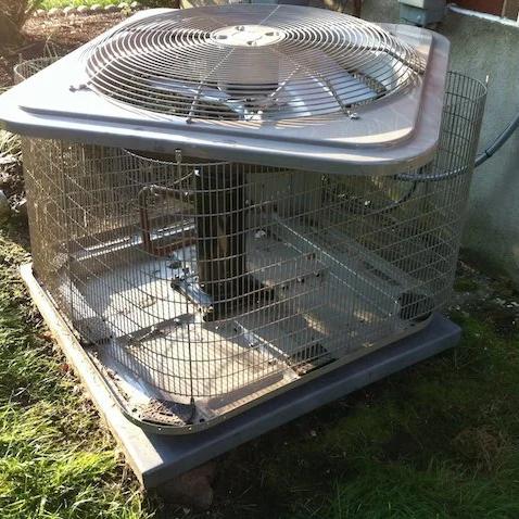 Outdoor air conditioning unit locked inside a metal security cage
