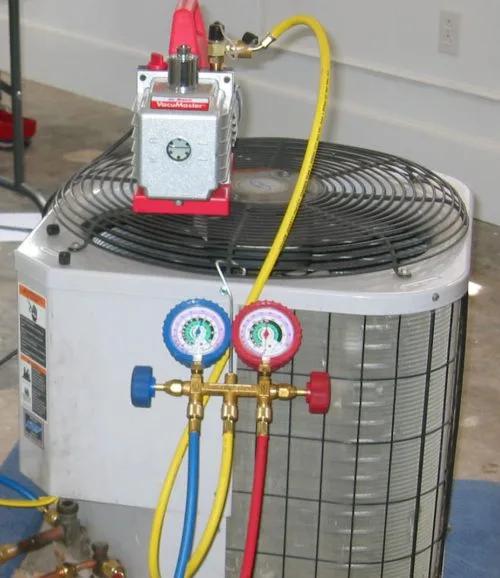 Vacuum pump and refrigerant gauges connected to an outdoor air conditioning unit