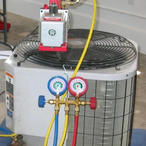 Vacuum pump and refrigerant gauges connected to an outdoor air conditioning unit