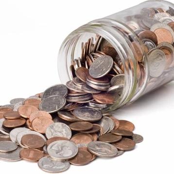 Jar of coins tipped over and spilling onto a white surface