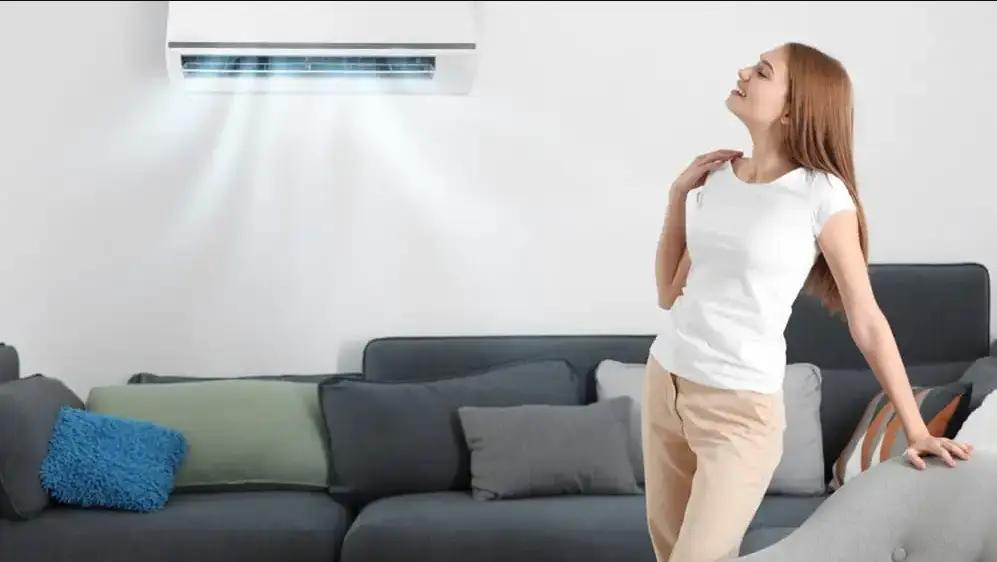 Woman relaxing on a couch beneath a wall-mounted ductless air conditioner