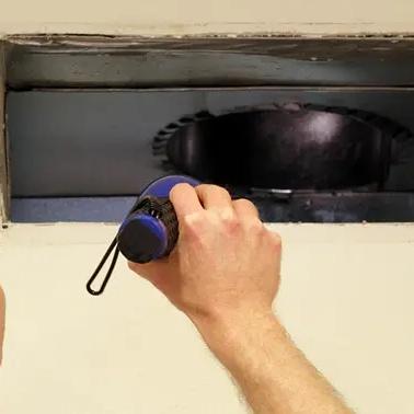 Man shining a flashlight into an open ceiling air duct