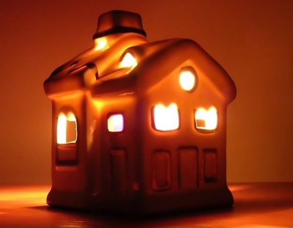 Ceramic house-shaped lantern glowing orange from within