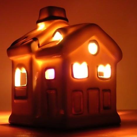 Ceramic house-shaped lantern glowing orange from within