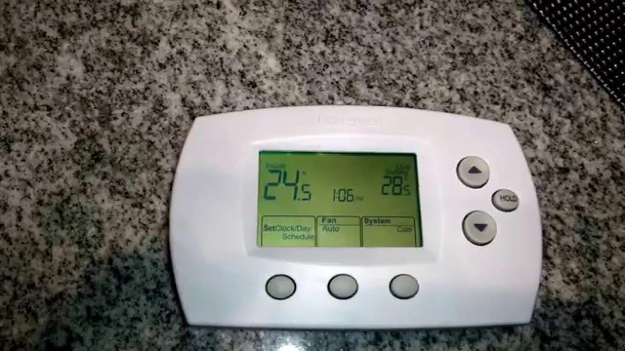 Digital thermostat with fan and system buttons resting on a granite countertop