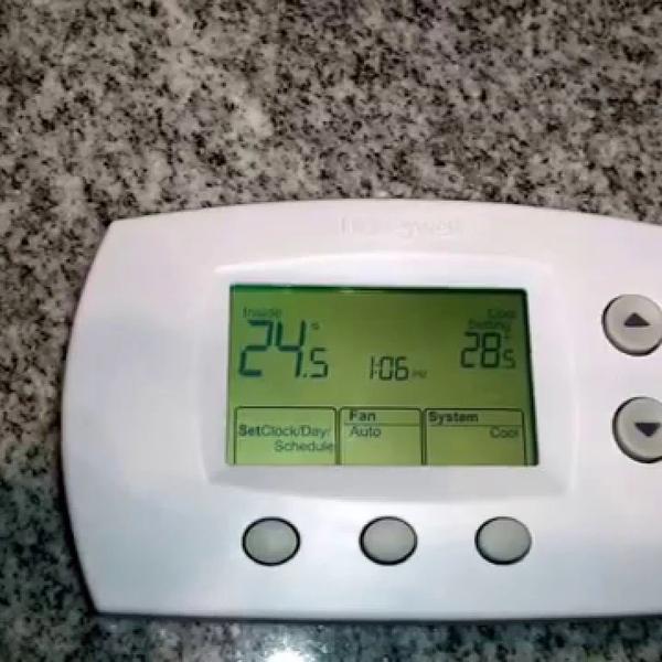 Digital thermostat with fan and system buttons resting on a granite countertop
