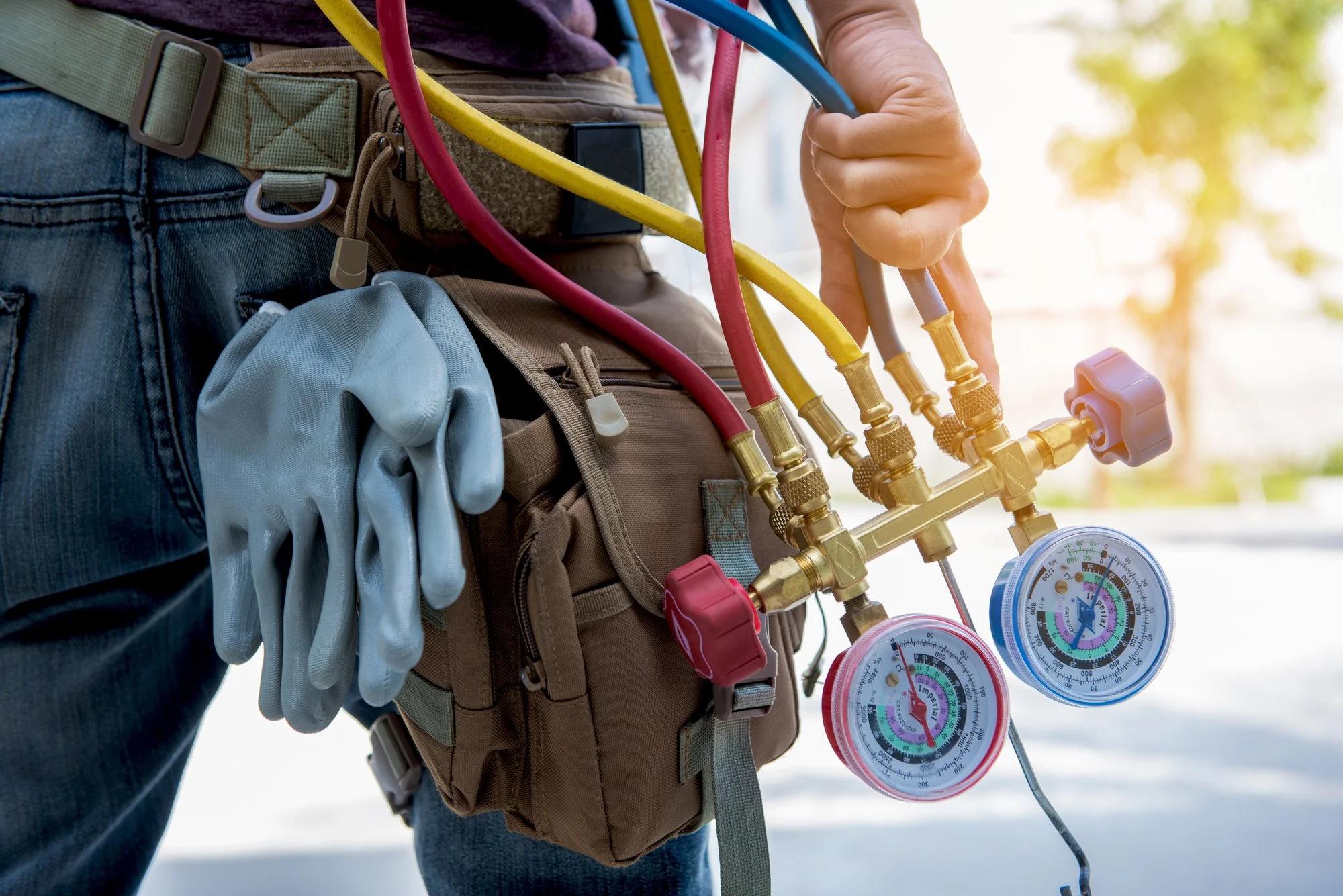 HVAC technician's tool belt with gloves and refrigerant gauges
