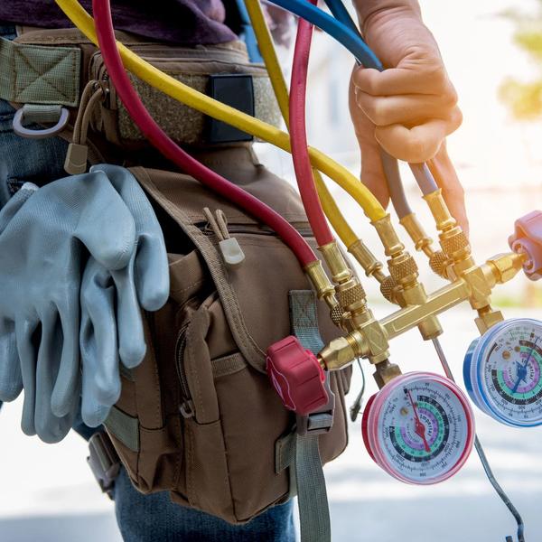 HVAC technician's tool belt with gloves and refrigerant gauges