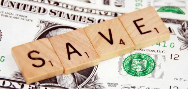 Scrabble tiles spelling "SAVE" on top of US dollar bills