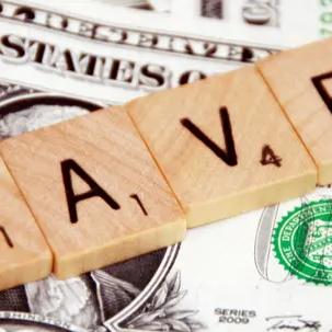 Scrabble tiles spelling "SAVE" on top of US dollar bills