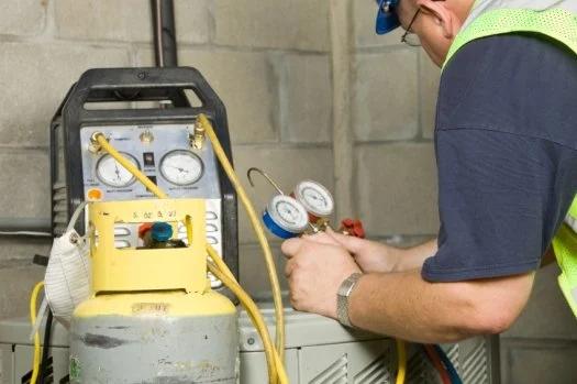 Technician using a refrigerant recovery machine and gauges on an HVAC system