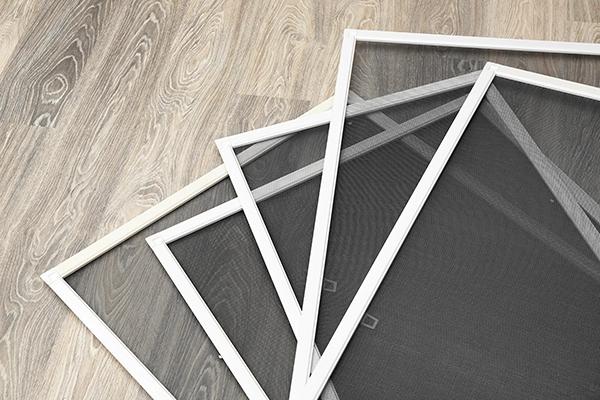 Stack of window screens on a wood floor