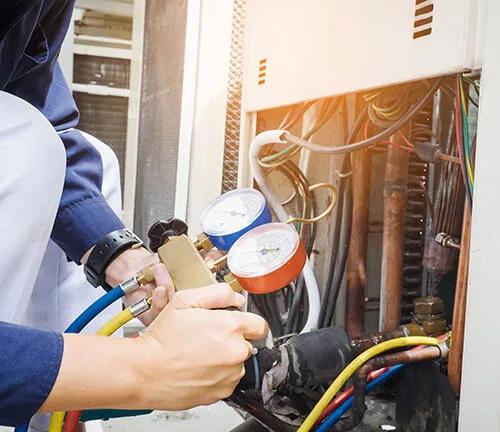 Technician connecting refrigerant gauges to an air conditioning unit