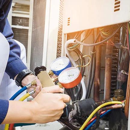 Technician connecting refrigerant gauges to an air conditioning unit