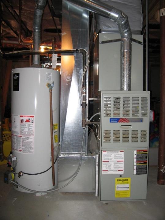 Old gas furnace beside a water heater in a basement