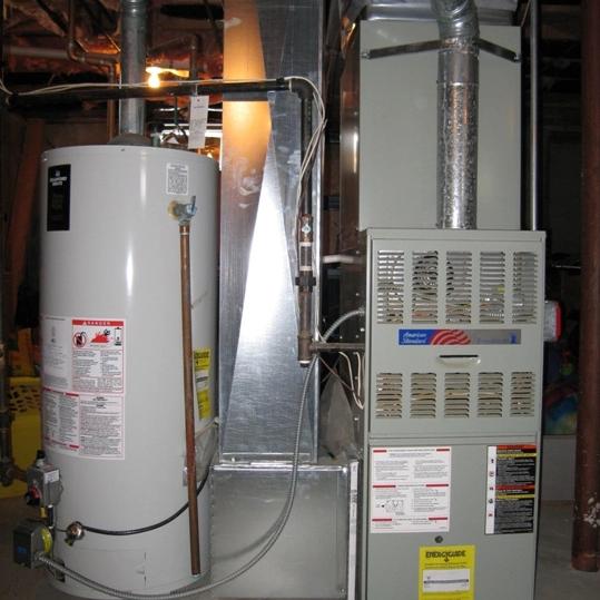 Old gas furnace beside a water heater in a basement