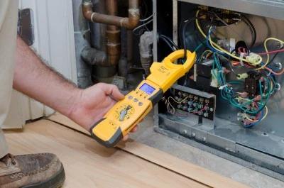Technician testing furnace wiring with a clamp meter