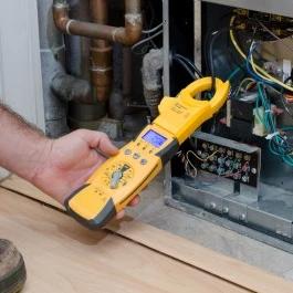 Technician testing furnace wiring with a clamp meter