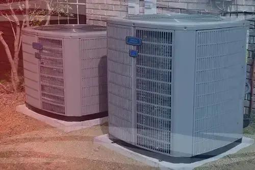 Two outdoor air conditioning units on concrete pads beside a house